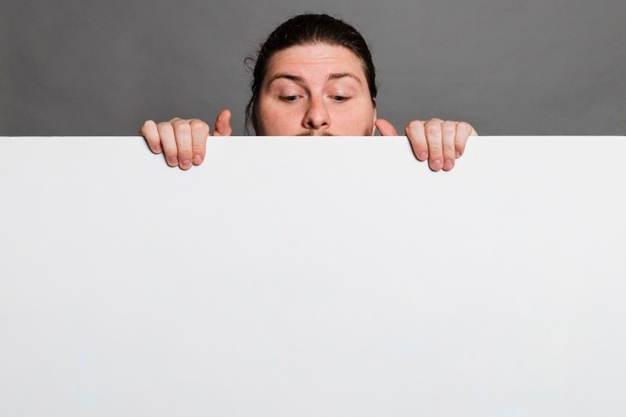close up man peeking white card paper against grey background 23 2148179599