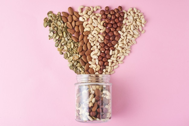 different types nuts seeds glass jar pink background top view 77190 3381