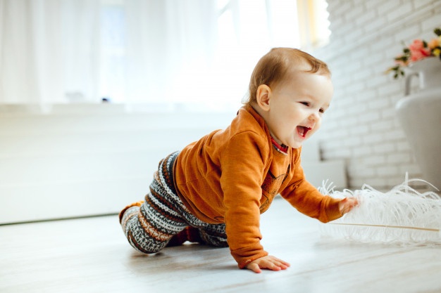 happy child orange sweater plays with feather floor 8353 182