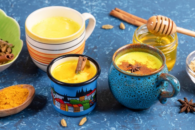 different cups with golden turmeric milk ingredients its cooking blue backdrop close up selective focus 121867 622