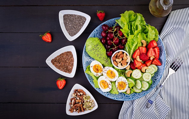 plate with paleo diet food boiled eggs avocado cucumber nuts cherry strawberries paleo breakfast top view 2829 17444