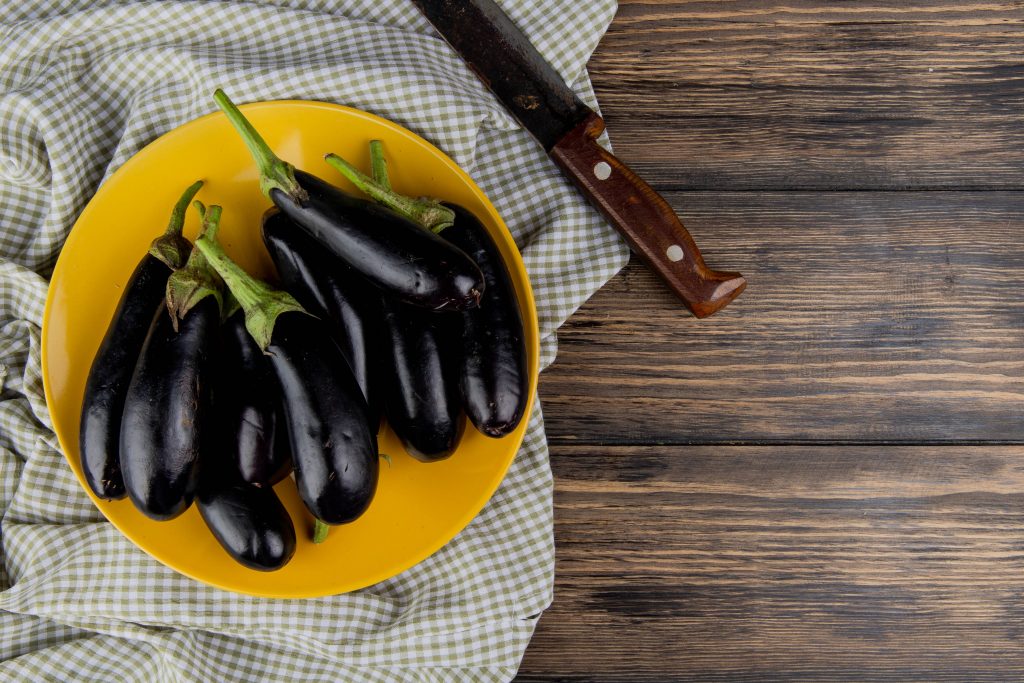 top view eggplants plate with knife cloth left side wooden background with copy space 2