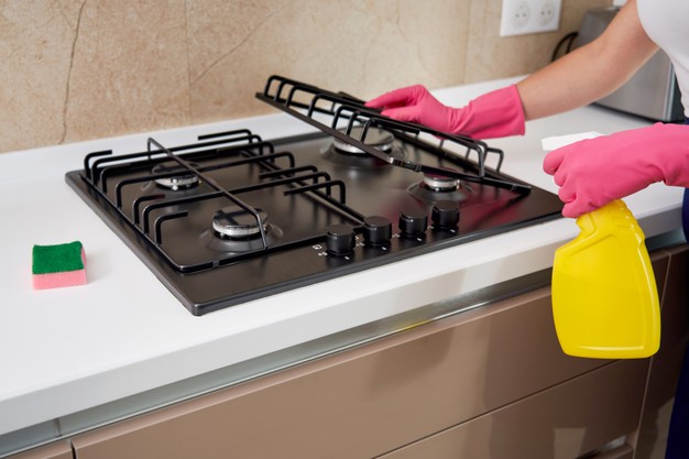 cleaning gas stove with kitchen utensils household concepts hygiene cleaning 130111 3586