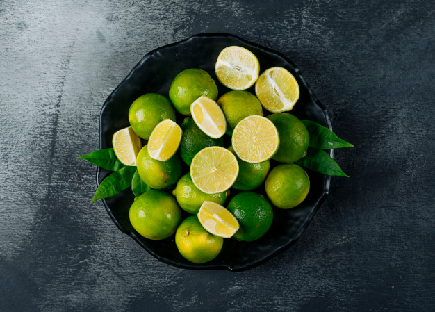 green lemons plate with slices top view black textured background 176474 3501